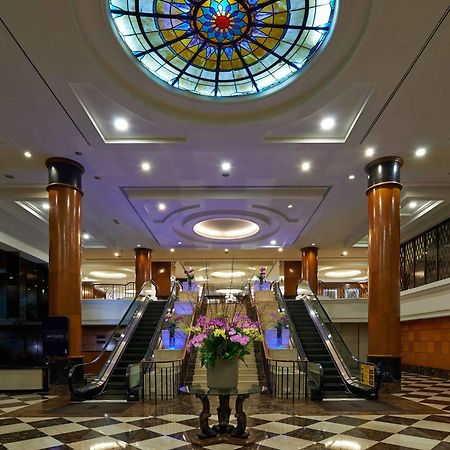 吉隆坡斯里太平洋酒店 外观 照片 The photo depicts an elegant hotel lobby featuring a large stained glass ceiling that adds a colorful touch to the space. The lobby has polished marble flooring with a checkerboard pattern. In the center, there is a beautiful arrangement of flowers i