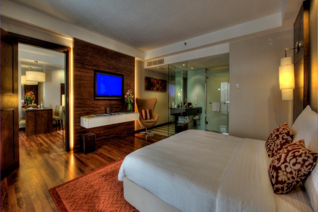 吉隆坡斯里太平洋酒店 外观 照片 The photo shows a modern hotel room featuring a large bed with white linens and decorative pillows. There is wood flooring and an area rug in front of the bed. A flat-screen television is mounted on the wall, and next to it is a stylish wooden dresse